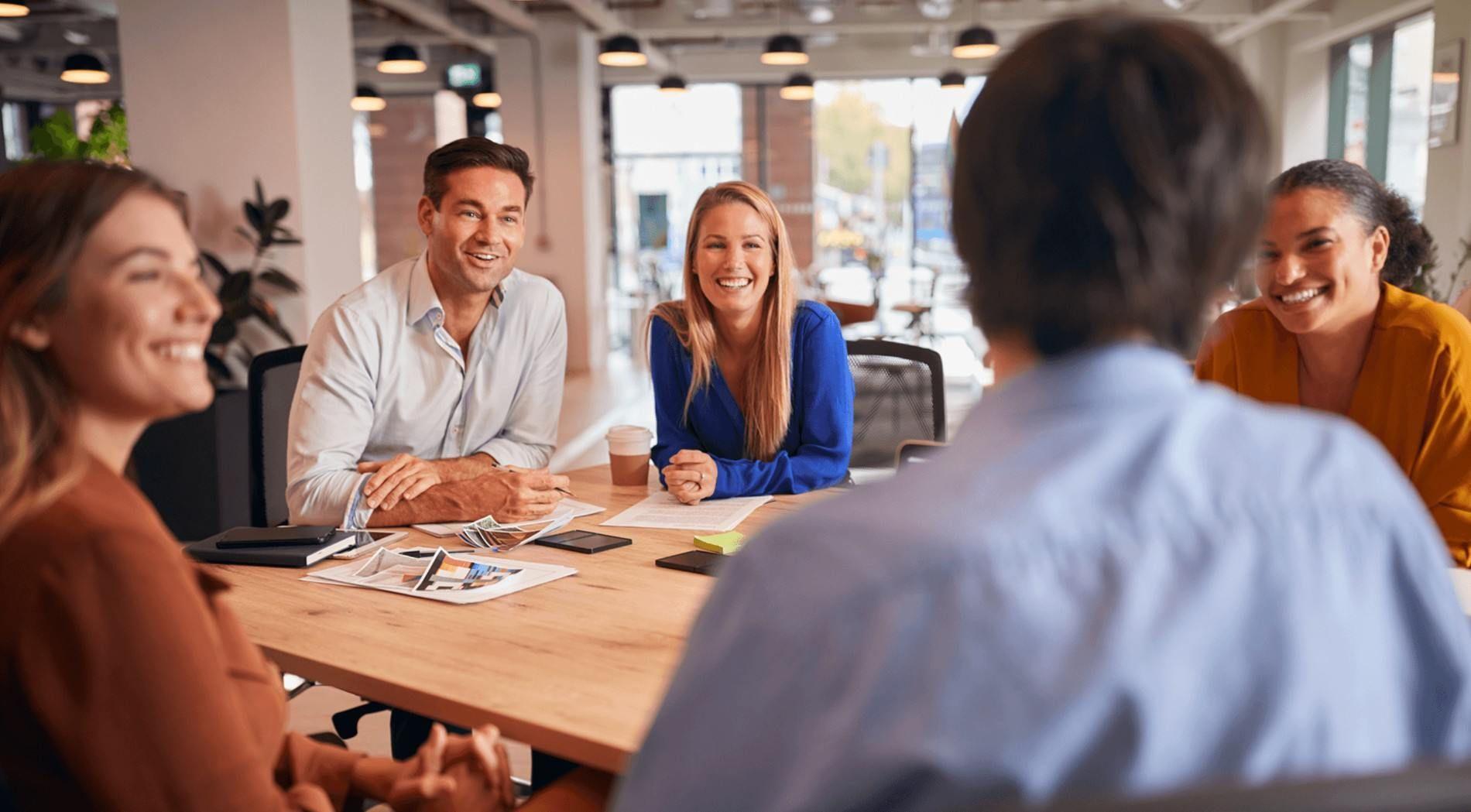 Groupe de freelances échangeant autour d’une table lors d’une réunion dans un espace de coworking.