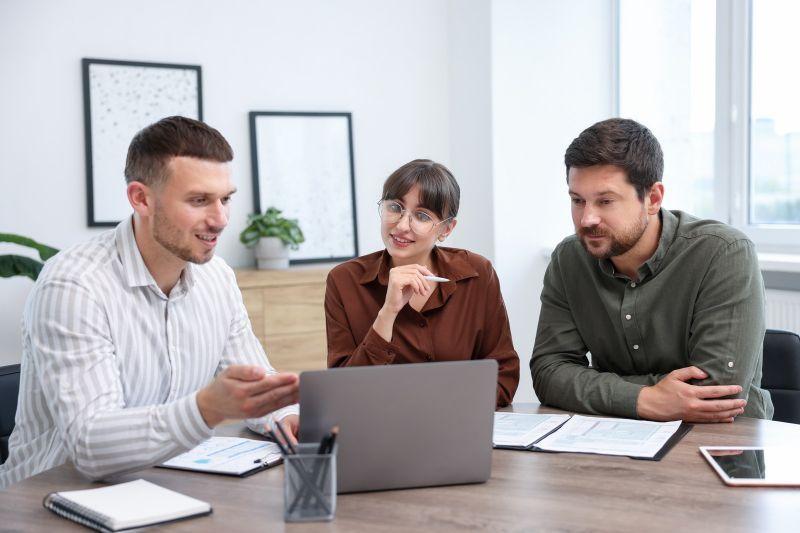 Three professionals reviewing information on a laptop during a collaborative meeting