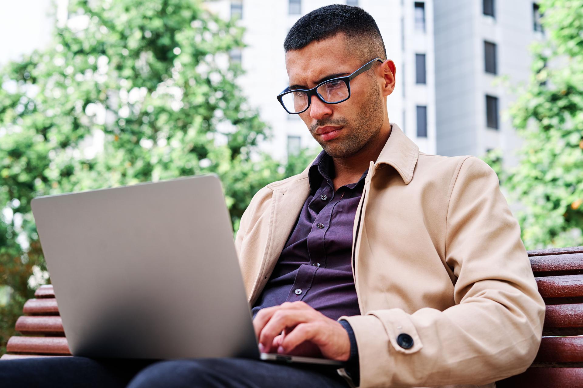 Man Working on Laptop Outdoors in Urban Setting