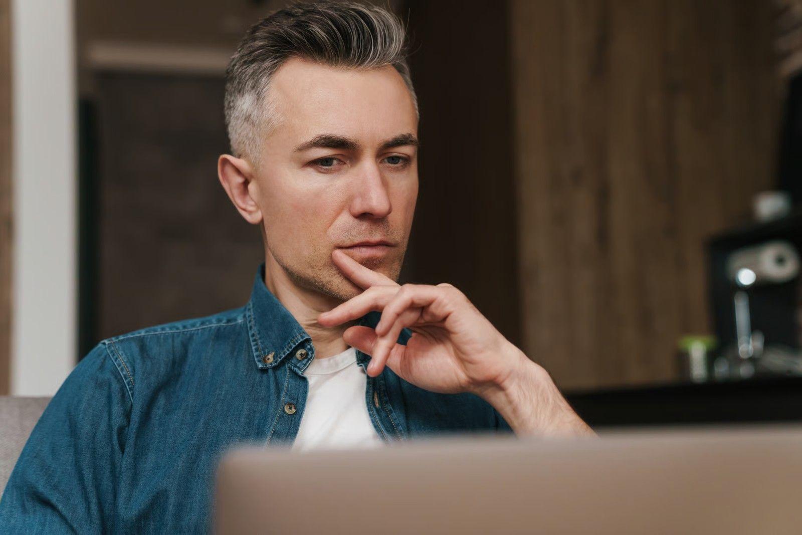 Thoughtful Man with Laptop Working from Home.