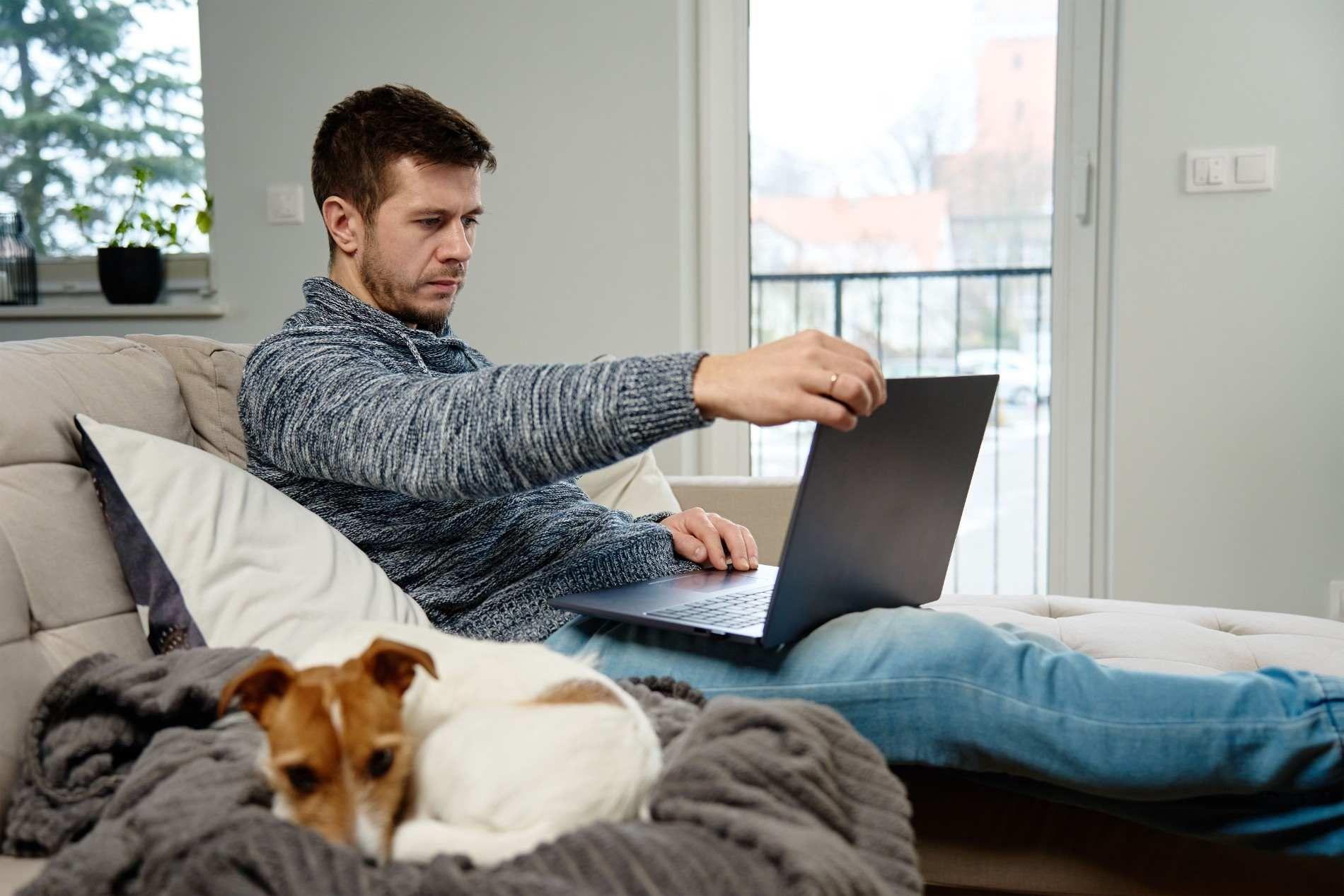 Freelancer on Couch with Laptop and Dog.