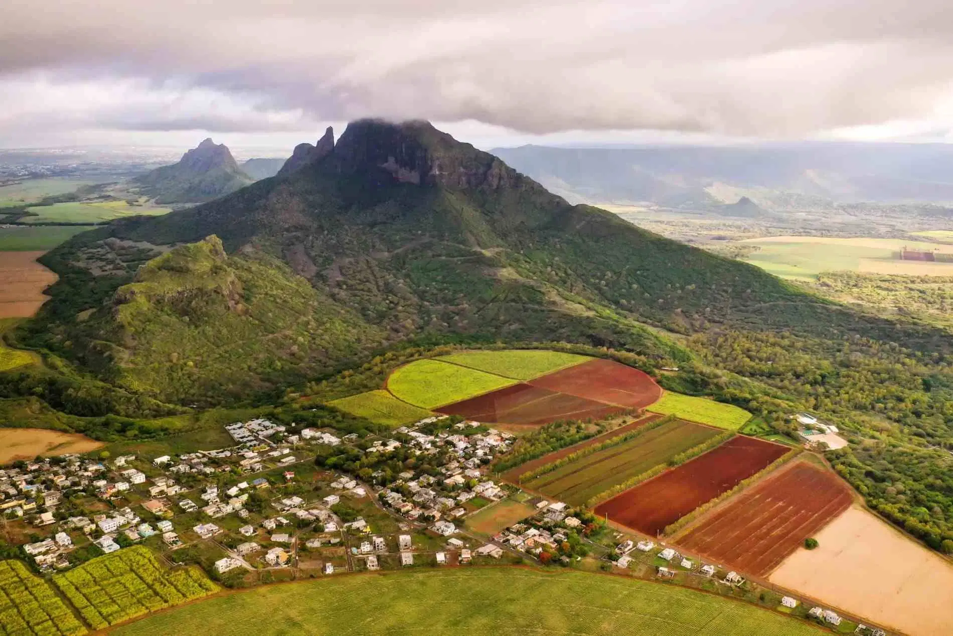 Aerial view of Mauritius with green mountains, farmland and a rural village.