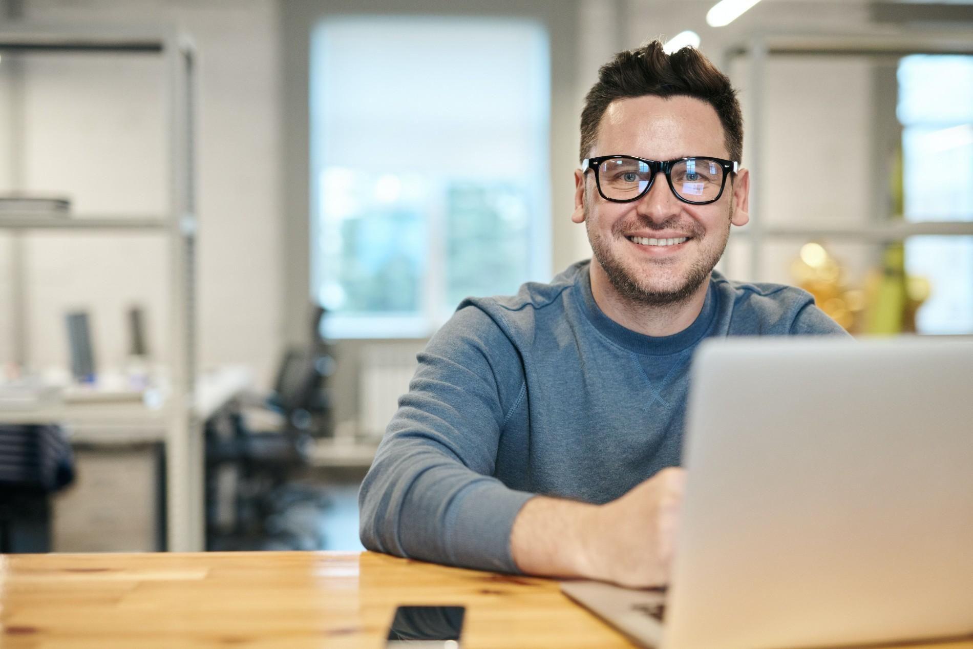 Smiling freelancer working on a laptop in a modern office.