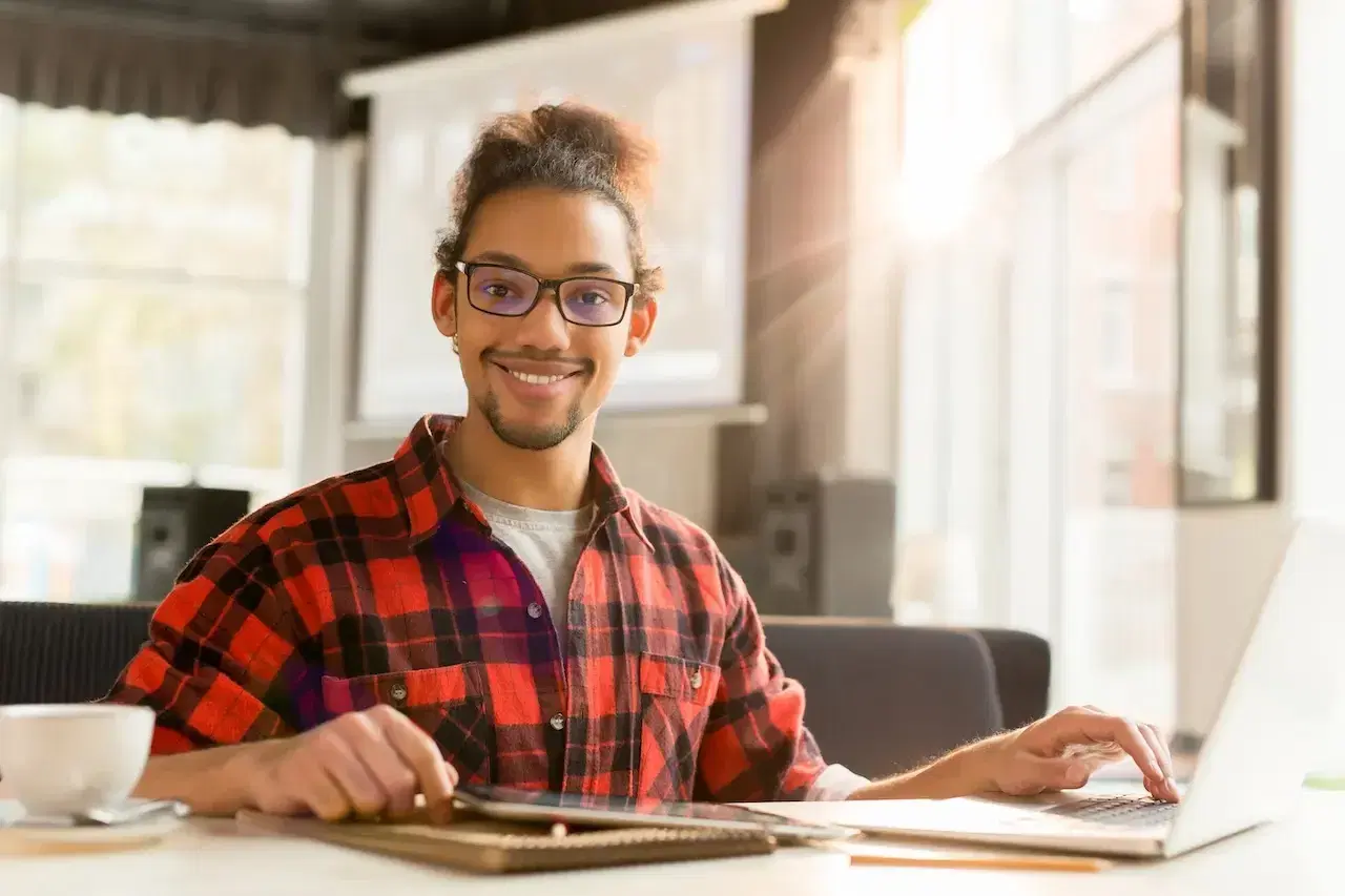 smiling man working on laptop at bright table
