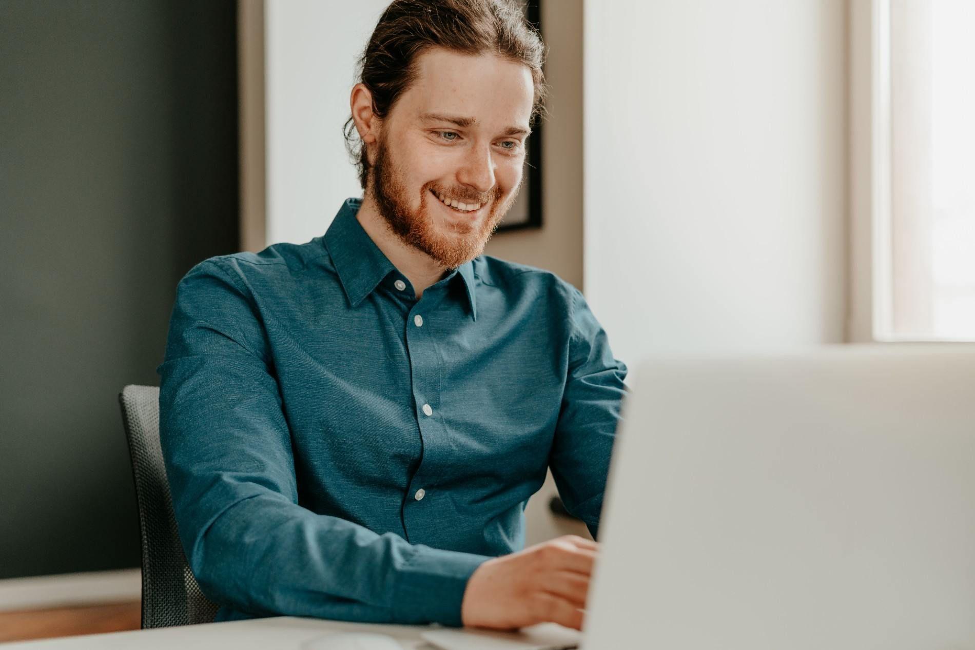 Smiling freelancer working on a laptop in a bright office.
