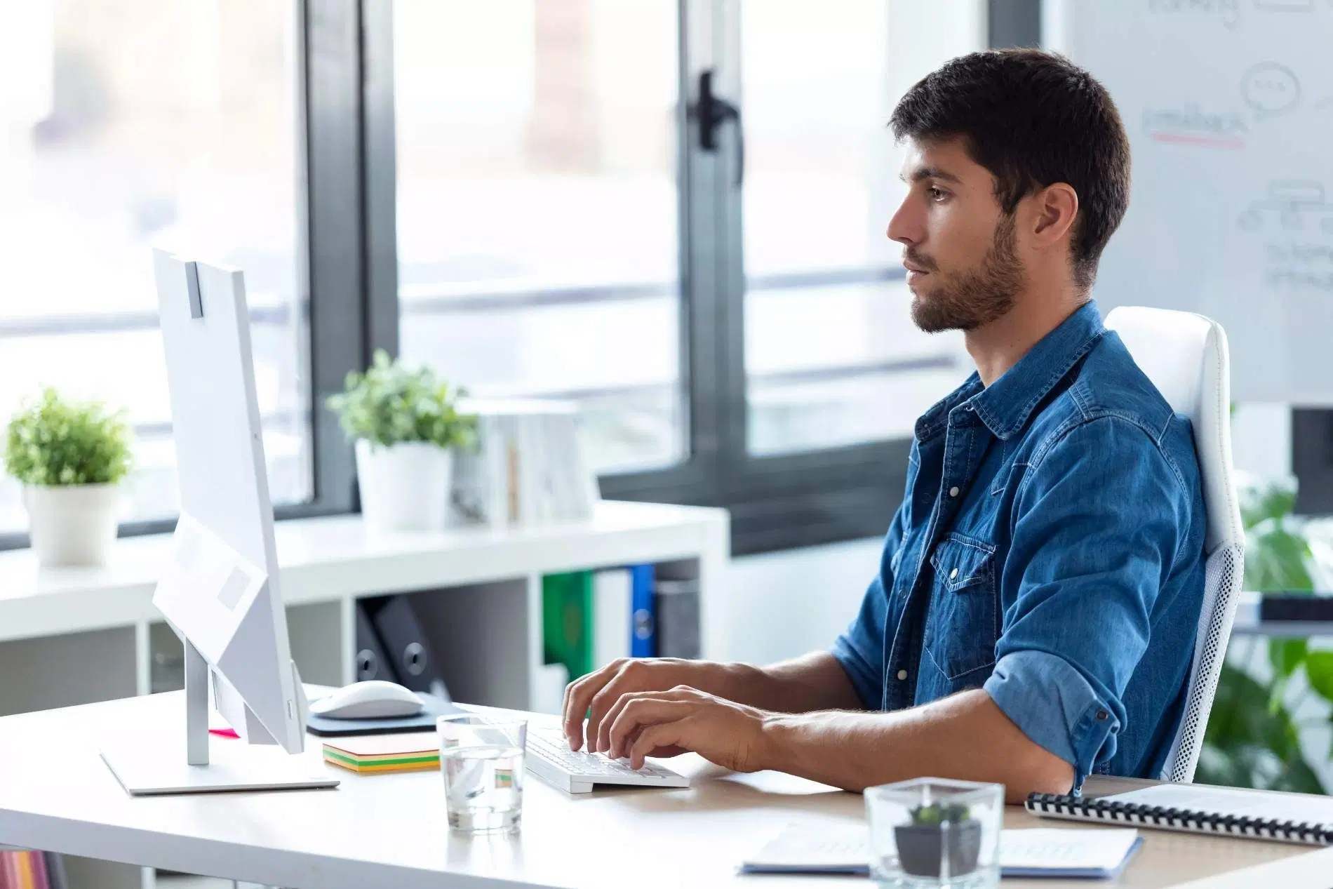 Freelance software developer working on a desktop computer in a modern office.