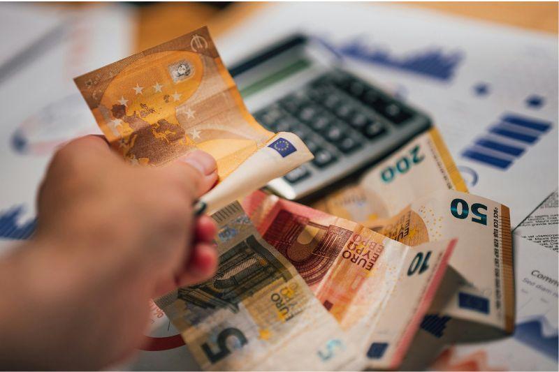 Hand holding euro banknotes illustrating umbrella company fees and payroll deductions