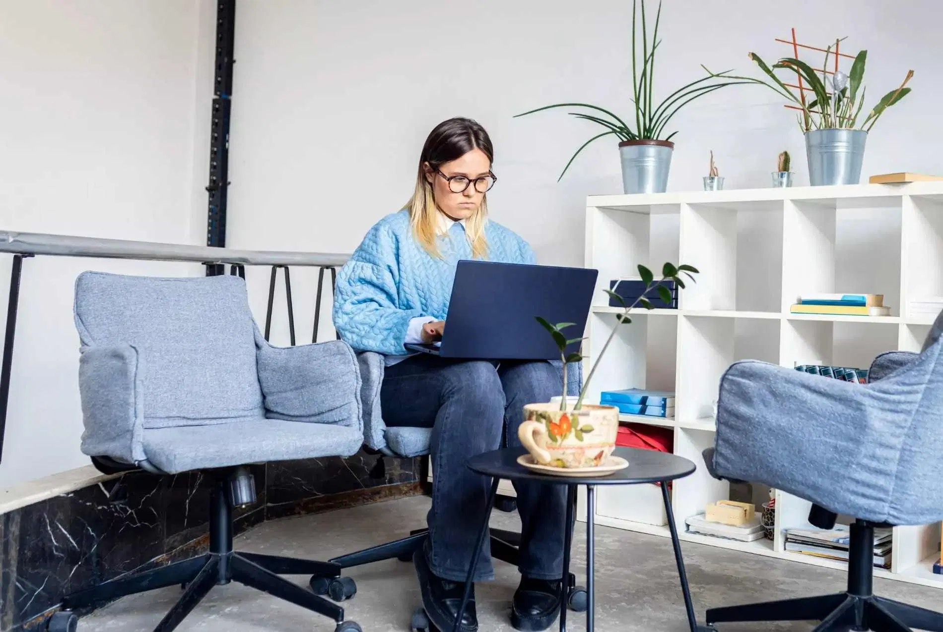 Woman working on a laptop while sitting in a modern coworking space.