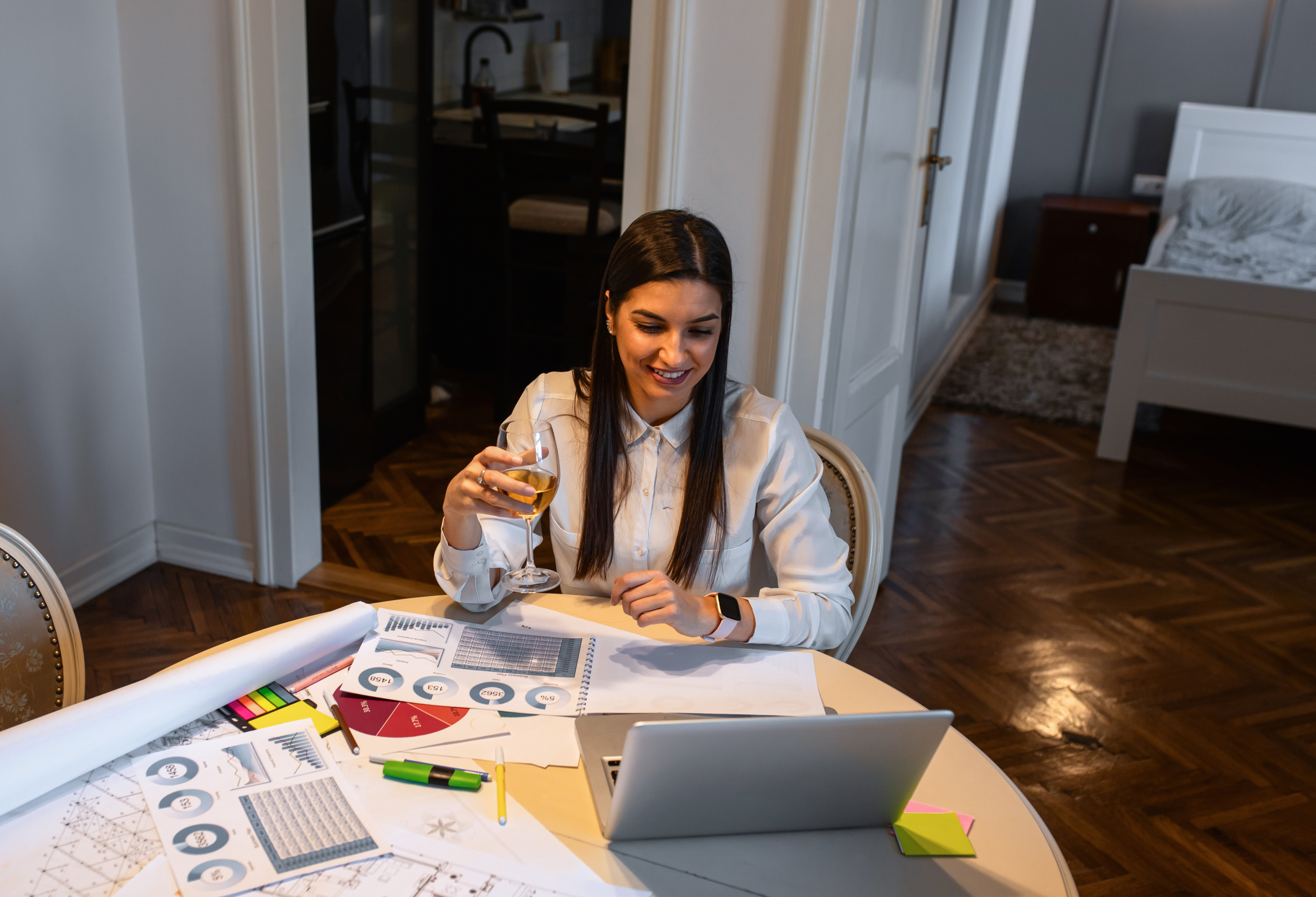 Smiling woman sitting in living room at home working using lapto